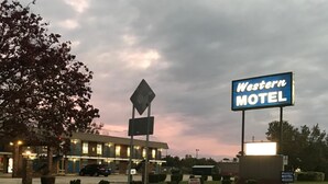 Schild eines Western-Motels, ein Gebäude mit einem Schild, das den Eingang zum Motel anzeigt, und eine Straße mit einer weißen Leitlinie.