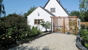 A white house with a gravel driveway and a wooden gate. - 3 bedroom accommodation in Bacton, near North Walsham (Bacton, near North Walsham)