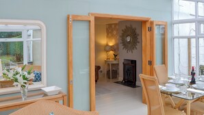 A dining area with a glass table, wicker chairs, a mirror, and a fireplace. - 3 bedroom accommodation in Bacton, near North Walsham (Bacton, near North Walsham)