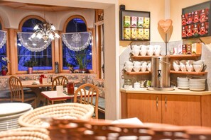 A cozy dining area with a table set for two, a coffee station, and a display of tea boxes.