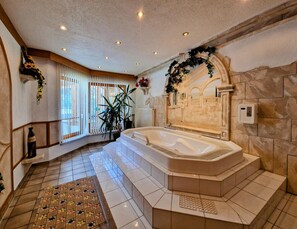 A spacious bathroom with a large bathtub, a shower area, and a tiled floor.