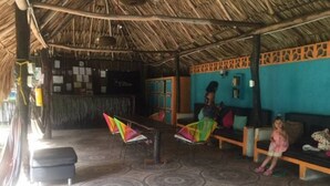A room with a thatched roof, a bar area, and a seating area with colorful chairs and a sofa. - IDESTINOS ROLLING HOUSE - PALOMINO (Palomino)