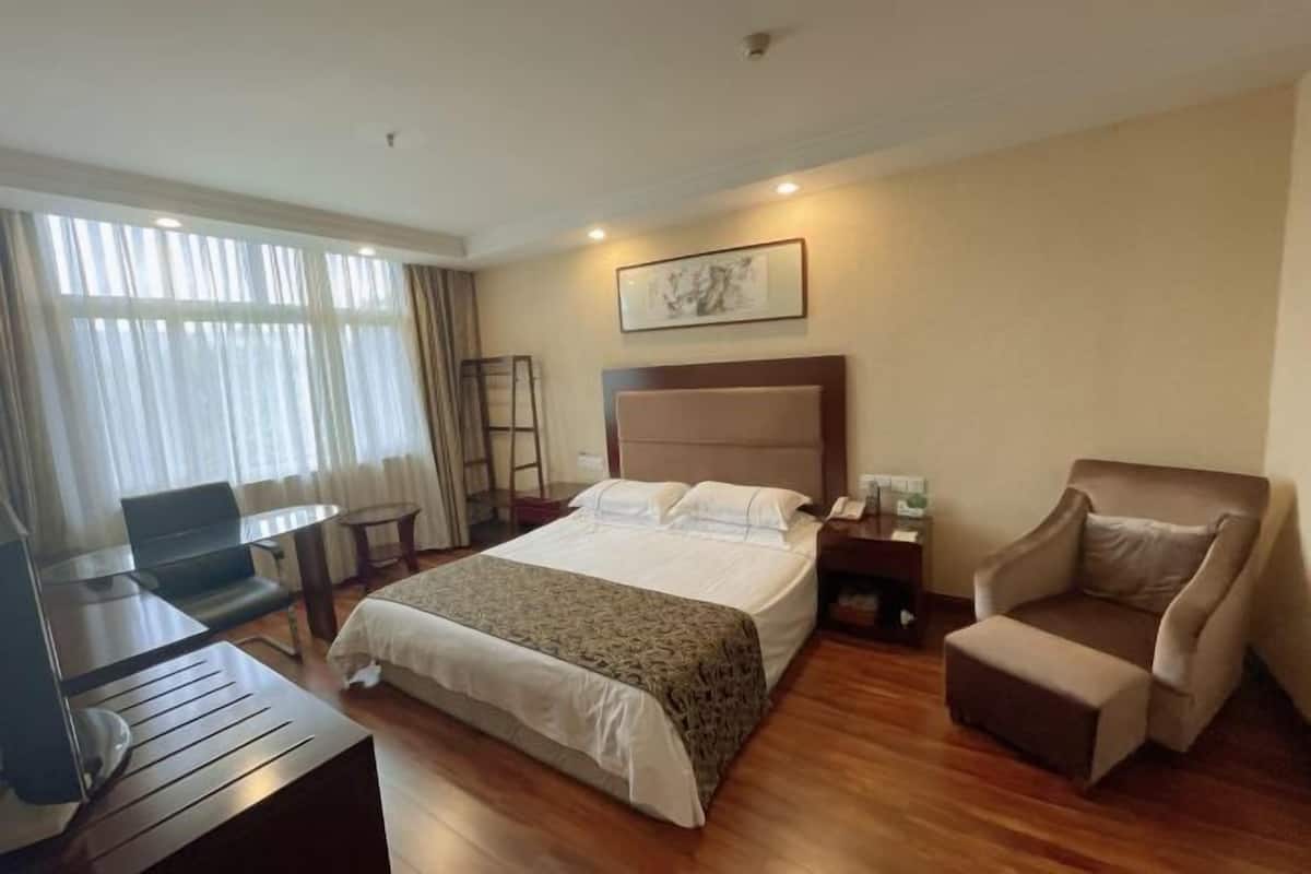 A hotel room with a bed, a desk, a chair, a small table, and a sofa.