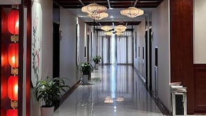 A hallway with a polished floor, hanging lanterns, and potted plants. - Huaian Hotel (Huai'an)