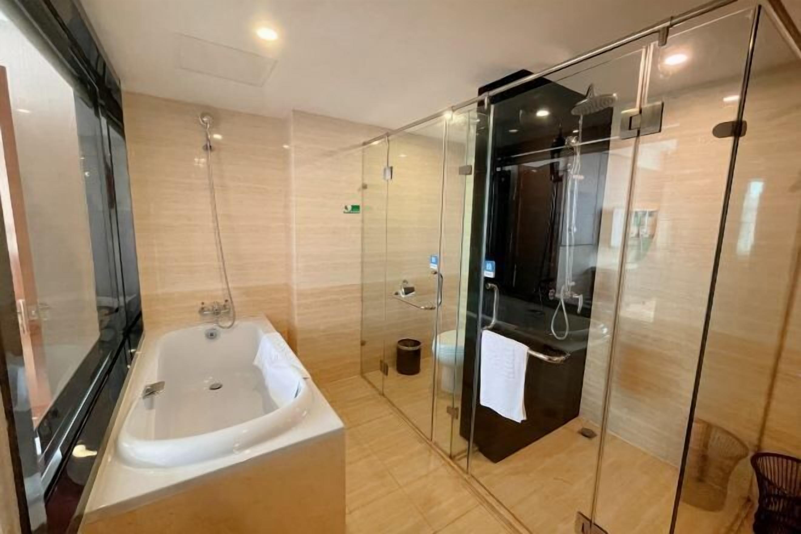 A modern bathroom with a glass-enclosed shower, a standalone bathtub, and a glass partition.