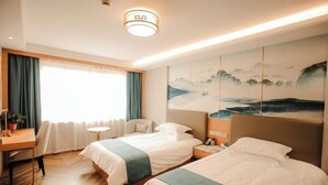 A hotel room with two beds, a desk, a chair, a small table, and a painting on the wall. - Huaian Hotel (Huai'an)