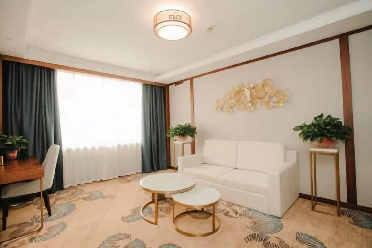 A modern living room with a white sofa, two round coffee tables, and a decorative wall piece.