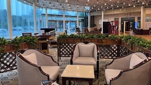 A spacious lobby with high ceilings, large windows, and a seating area with cushioned chairs and a small table. - Huaian Hotel (Huai'an)