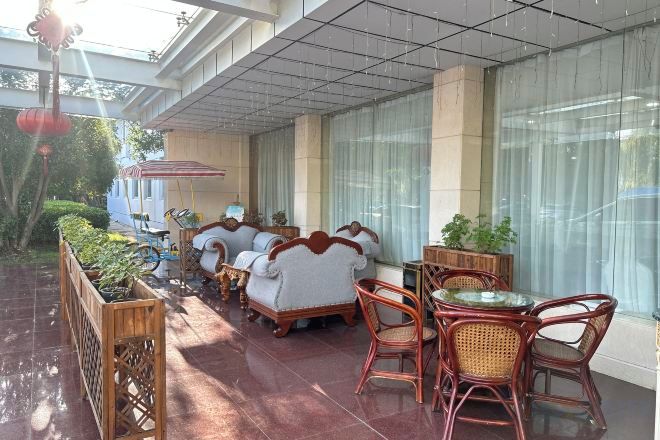 A covered outdoor seating area with wicker furniture and a glass table.