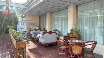 A covered outdoor seating area with wicker furniture and a glass table.