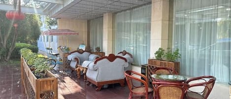 A covered outdoor seating area with wicker furniture and a glass table.