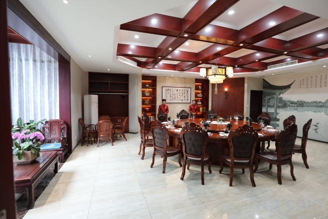 A traditional dining area with a round table, chairs, and a ceiling with wooden beams.