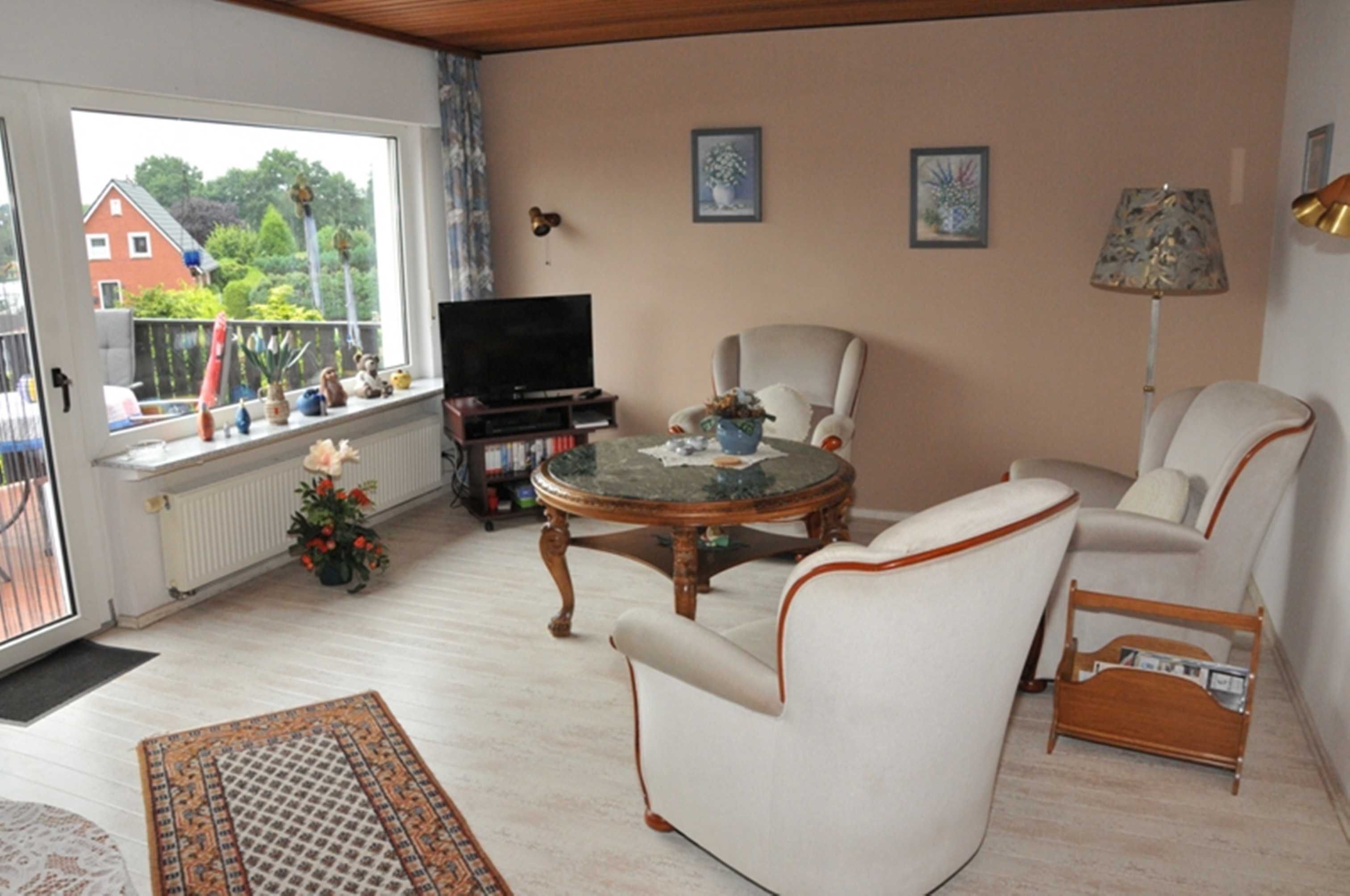 A living room with a television, a round table, and two armchairs.