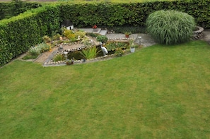 A well-maintained garden with a pond, a variety of plants, and a small structure. - Ferienwohnung Bruns 15028 - Nur für Urlaubsgäste! - Ferienwohnung Bruns (Leer (Ostfriesland))
