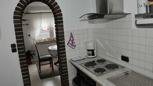 Uma cozinha com fogão, cafeteira e janela com cortinas.