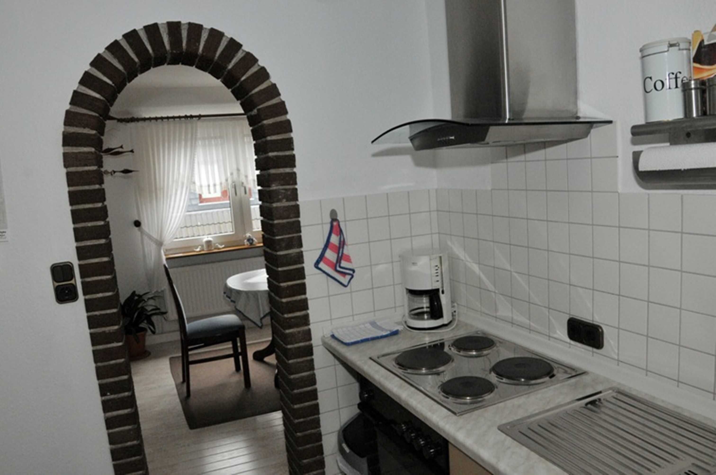 Une cuisine équipée d’une cuisinière, d’une machine à café et d’une fenêtre avec des rideaux.