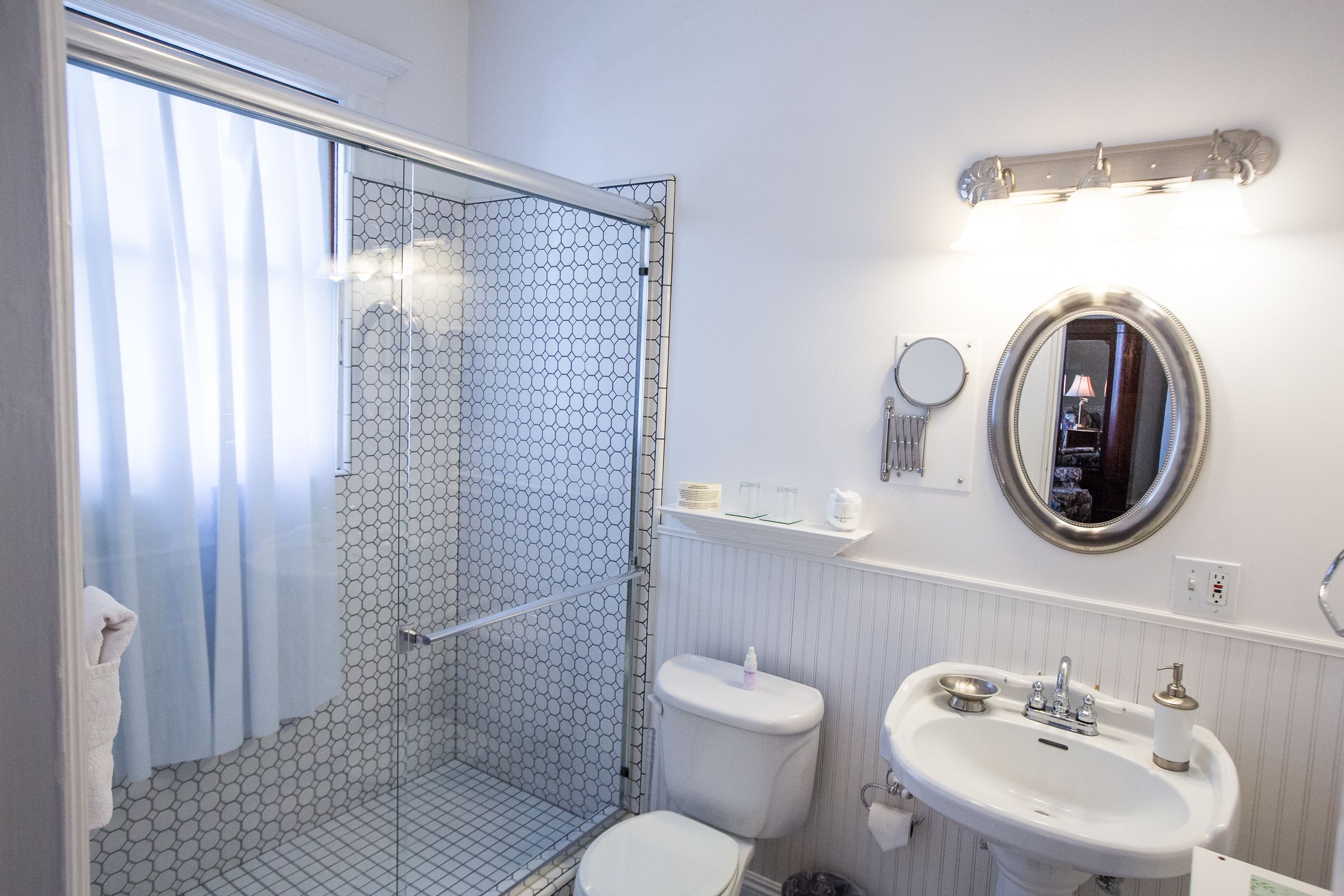 Un baño con ducha envuelta en vidrio, inodoro, lavabo y espejo.
