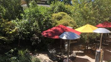 A patio area with outdoor seating, surrounded by lush greenery and trees.