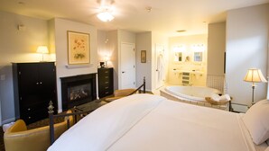 A hotel room with a large bed, a fireplace, a bathroom with a bathtub, and a mirror. - The Inn On First (Napa)