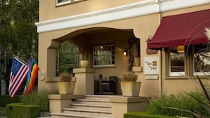 A hotel entrance with a covered porch, steps leading to the door, and a sign indicating it's the first hotel. - The Inn On First (Napa)