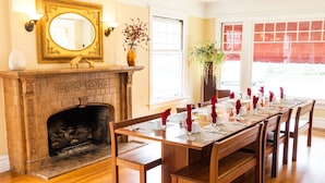A dining room with a fireplace, a long wooden table set for a meal, and a large mirror above the fireplace. - The Inn On First (Napa)