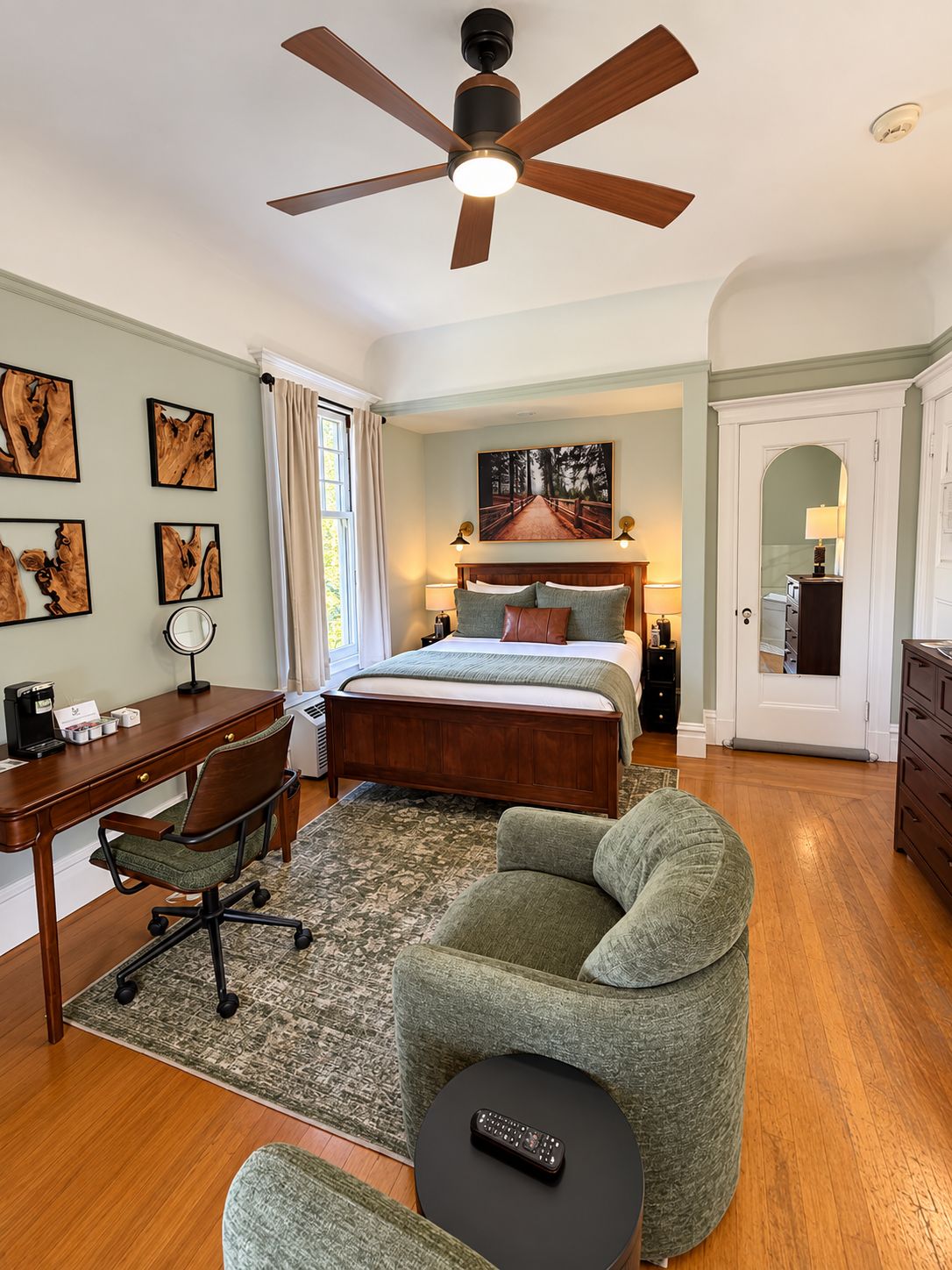 A bedroom with a bed, desk, chair, and a ceiling fan.