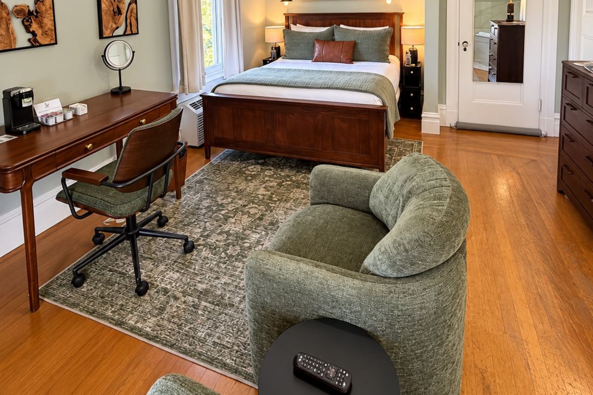 Une chambre à coucher avec un lit, un bureau, une chaise et un ventilateur de plafond.