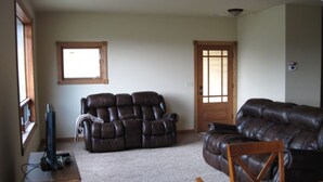 A living room with a large brown leather sofa, a recliner, and a television on a stand.