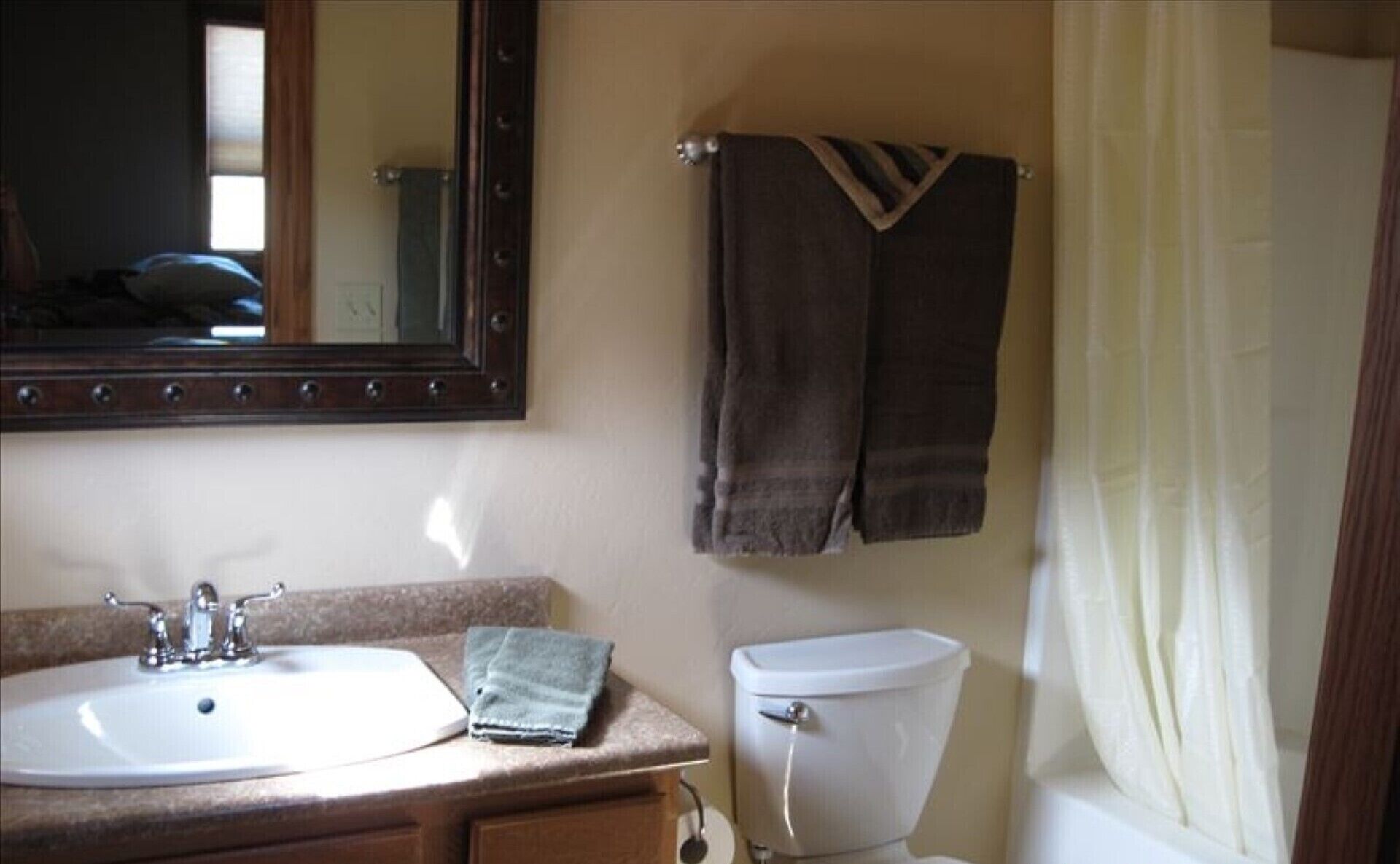 Un baño con lavamanos, espejo, toallero, inodoro y cortina de ducha.