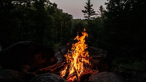 Un feu de camp entouré de rochers et d’arbres.