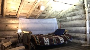Une chambre aménagée dans un chalet en rondins, avec un lit, une petite table et une chaise.