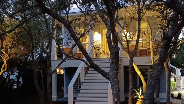 Ein modernes Haus mit einer Treppe, die zu einem oberen Stockwerk führt, umgeben von Bäumen.