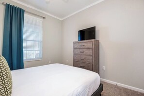 Een slaapkamer met een bed, een dressoir en een televisie erboven.