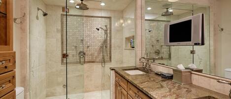 A modern bathroom with a glass-enclosed shower, a vanity with a sink, and a large mirror.
