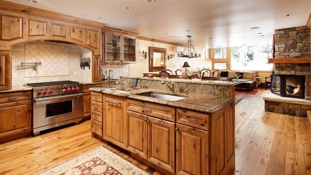 A spacious kitchen with wooden cabinets, a built-in stove, granite countertops, and a stone fireplace. - Pet Friendly & Luxurious 3 bedroom Aspen Condo (Aspen)