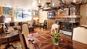 A cozy living room with a fireplace, large windows, and a dining area. - Pet Friendly & Luxurious 3 bedroom Aspen Condo (Aspen)