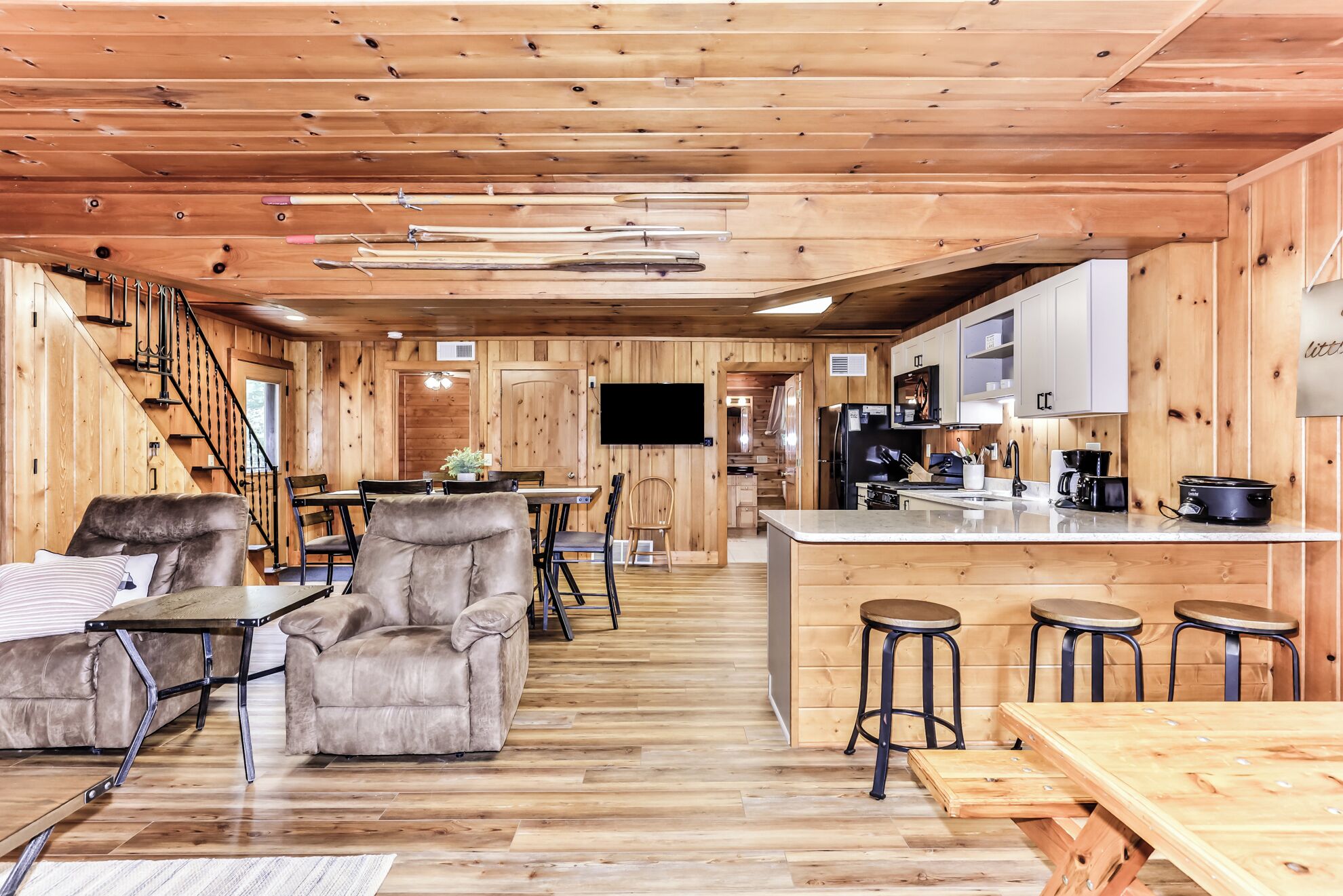 Un intérieur de chalet chaleureux comprenant un coin repas, une cuisine et un escalier menant à un niveau supérieur.