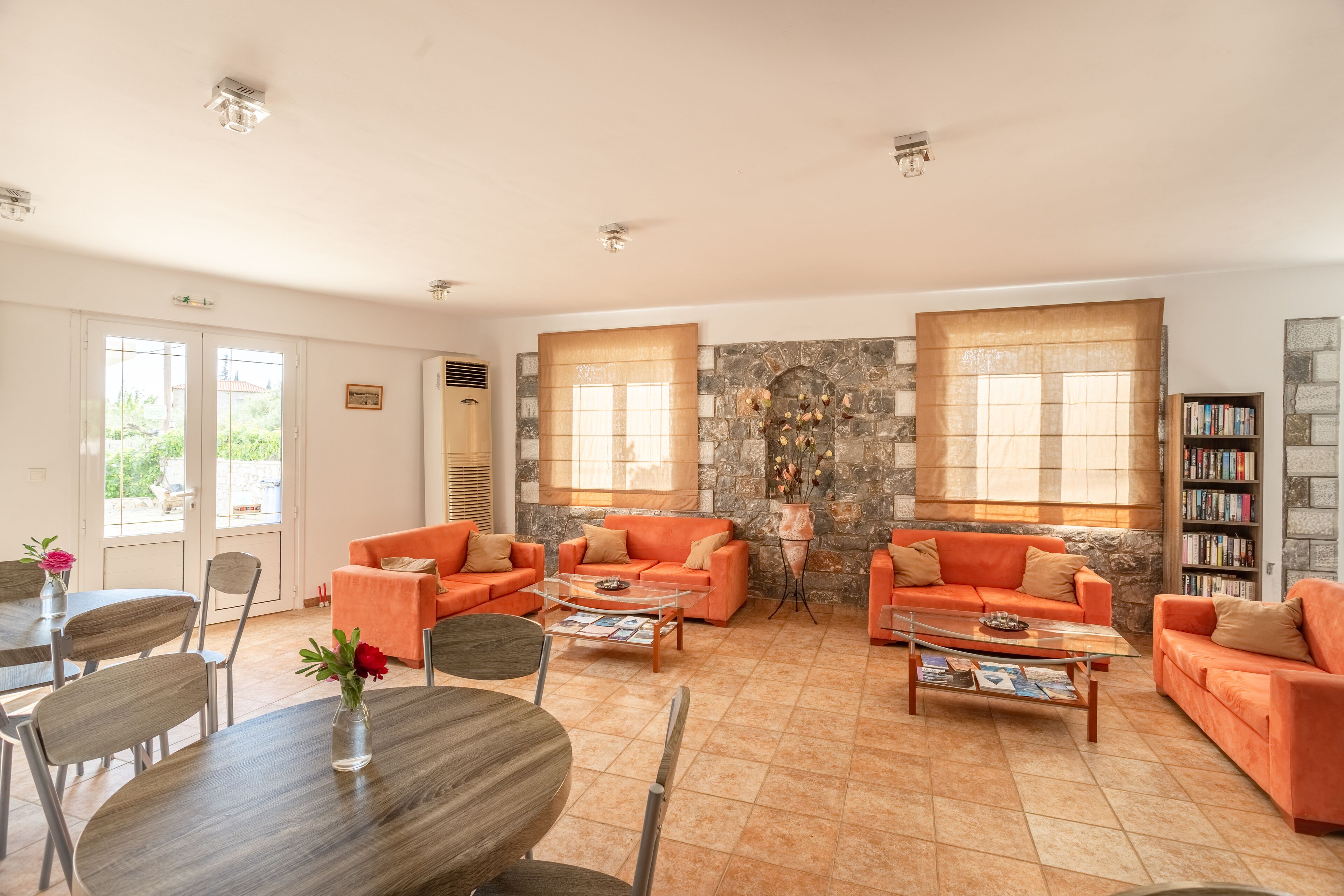 A spacious living room with orange sofas, a wooden coffee table, and a stone wall.