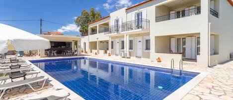 Una piscina al aire libre de temporada, sombrillas