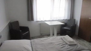 A hotel room with a bed, two chairs, a small table, and a window with curtains. - Landhotel Lippach (Westhausen)