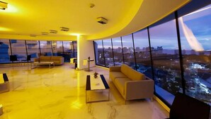A modern interior with a curved ceiling, large windows offering a city view, and contemporary furniture. - Don Majestic Hotel Punta del Este (Punta del Este)