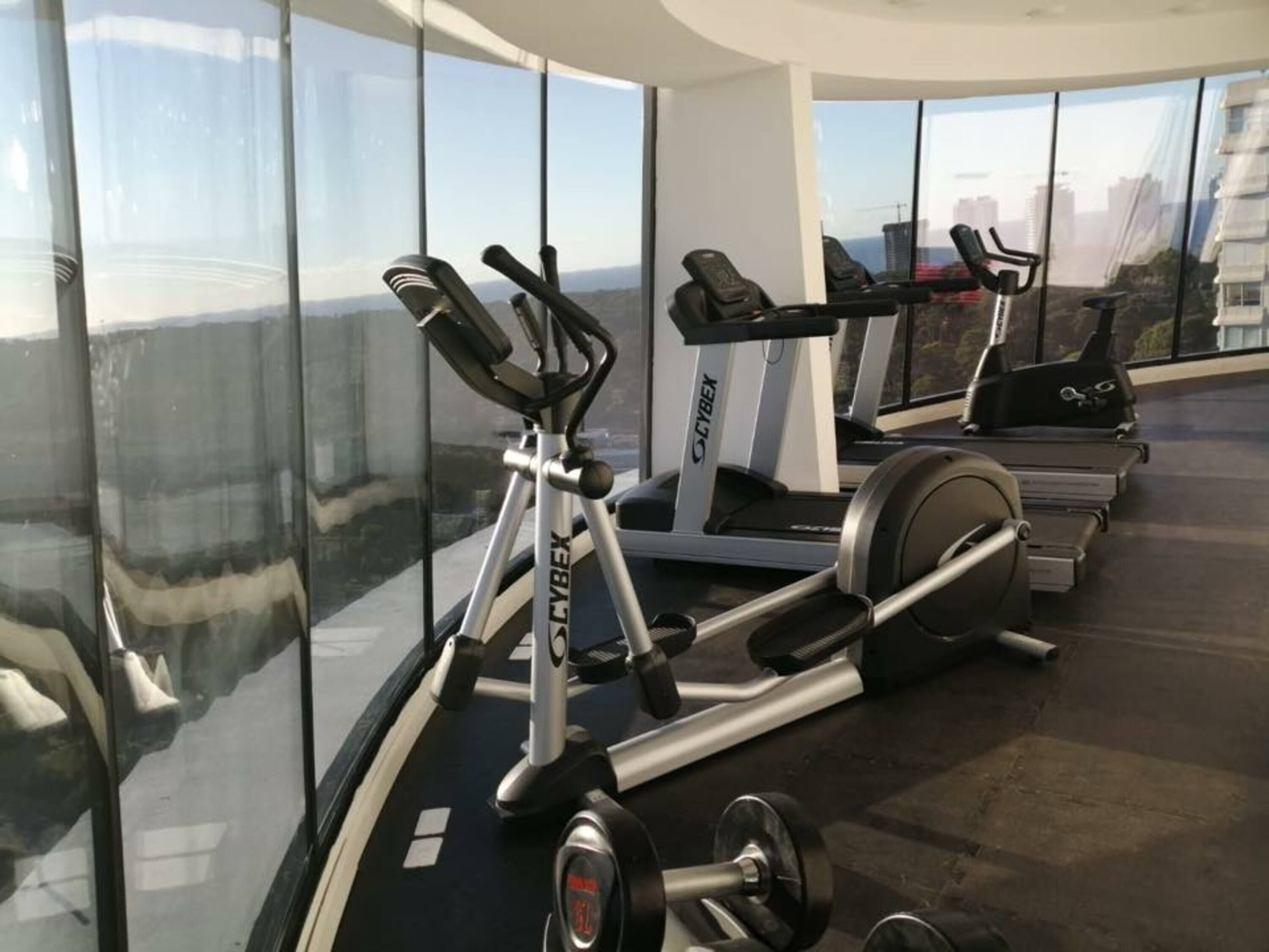 A gym with cardio machines and a weight bench.