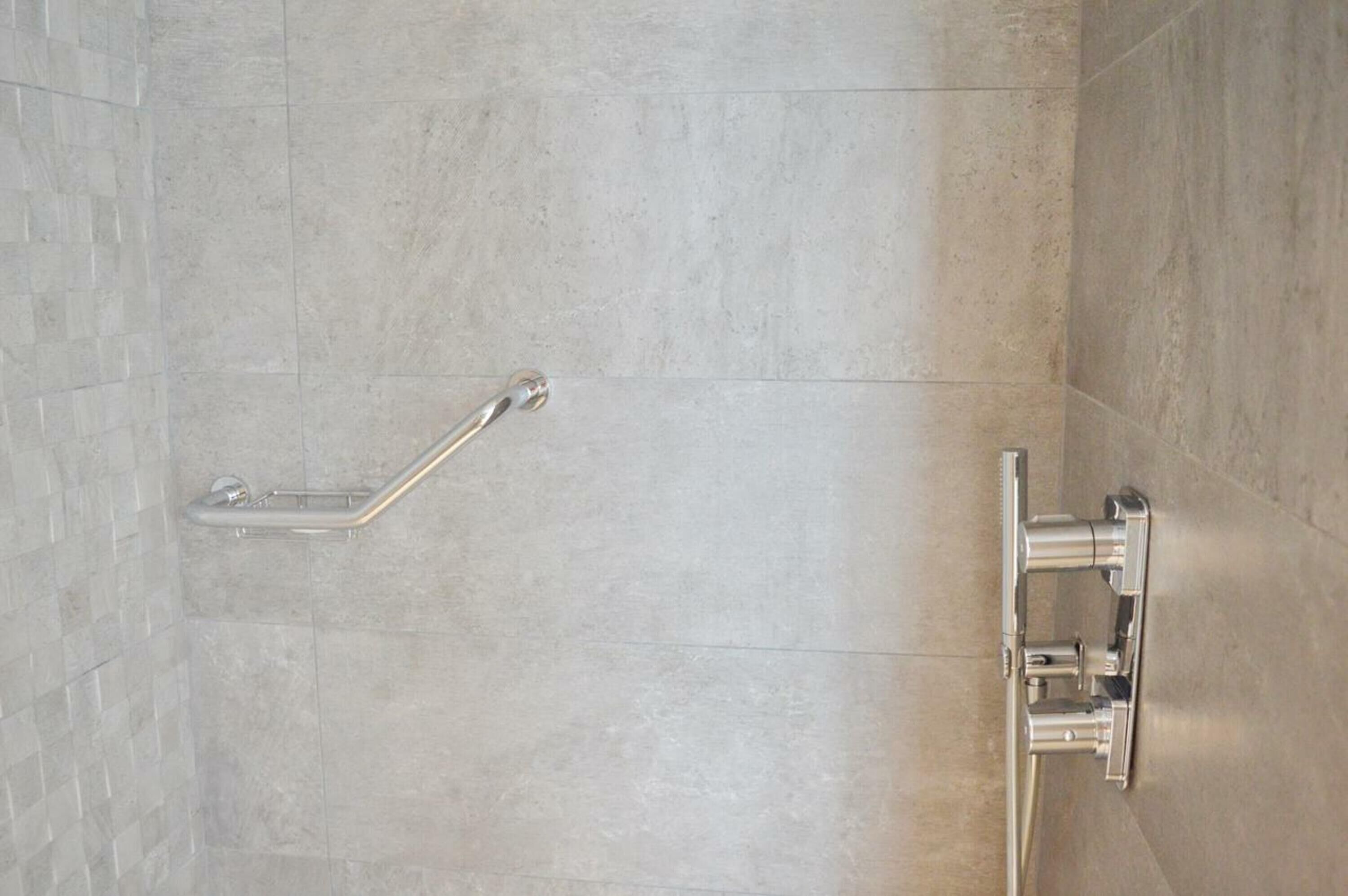 A shower area with a grab bar and a towel rack.