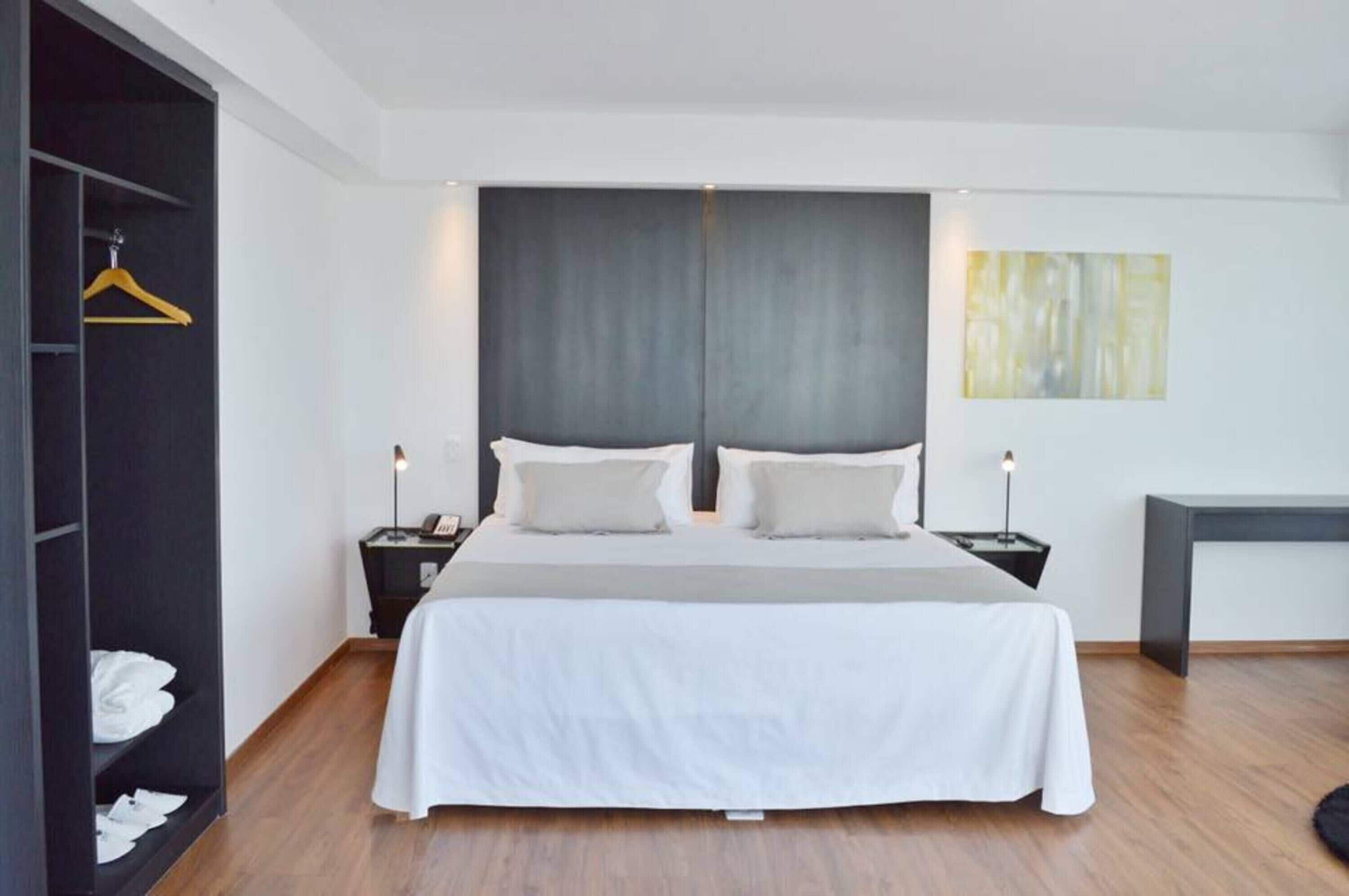 Et moderne hotelværelse med en stor seng, sengeborde, et garderobeskab og et skrivebord.