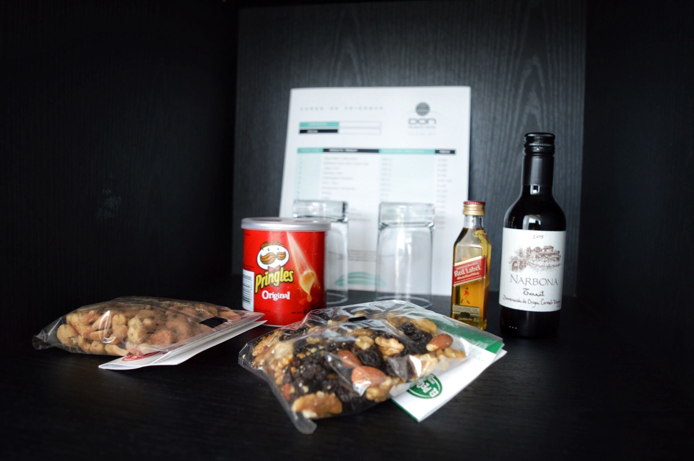 Una mesa con aperitivos, una botella de vino y un menú.