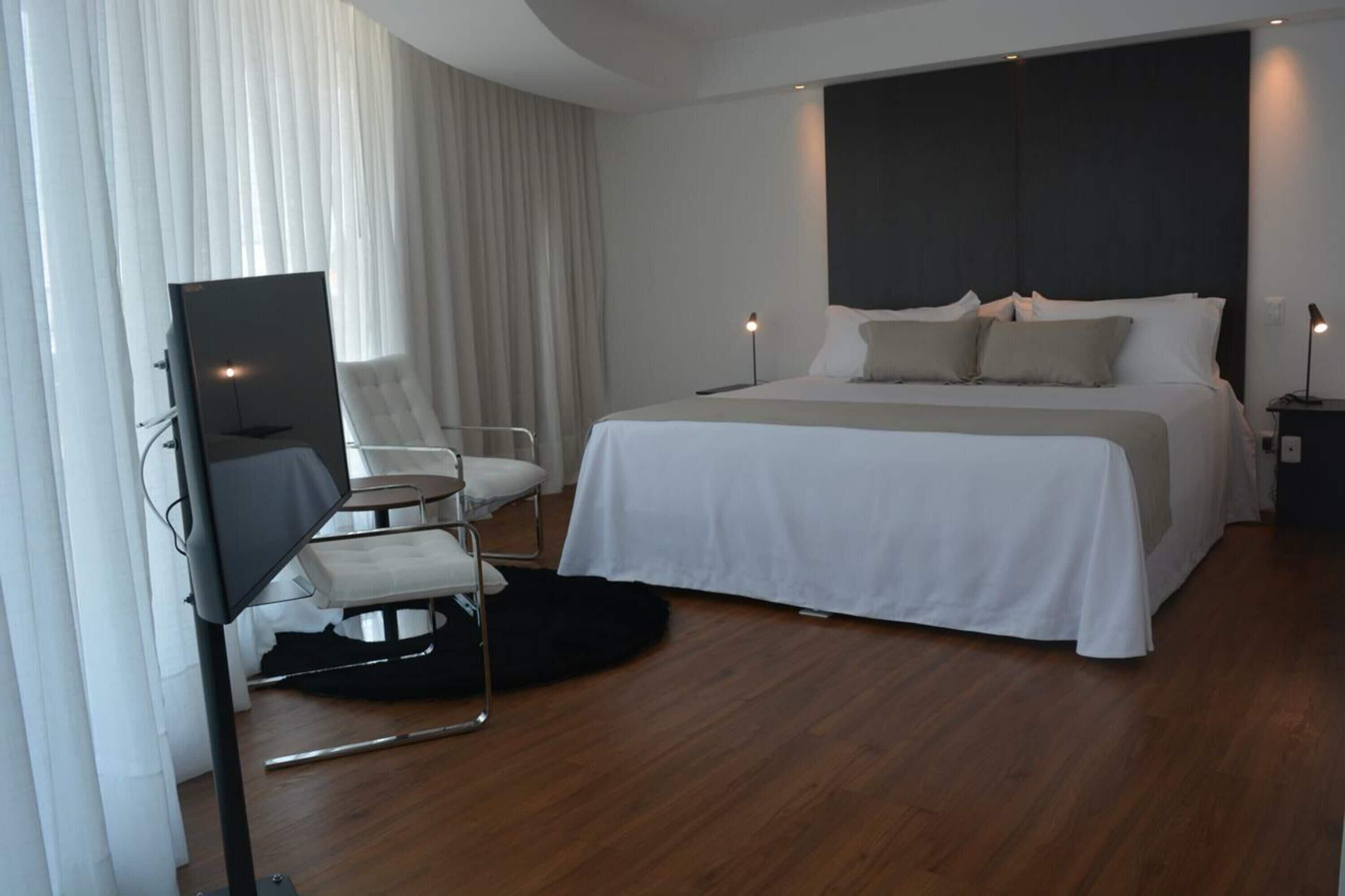 Une chambre d’hôtel moderne équipée d’un grand lit, d’une télévision à écran plat, d’une chaise et d’un bureau.