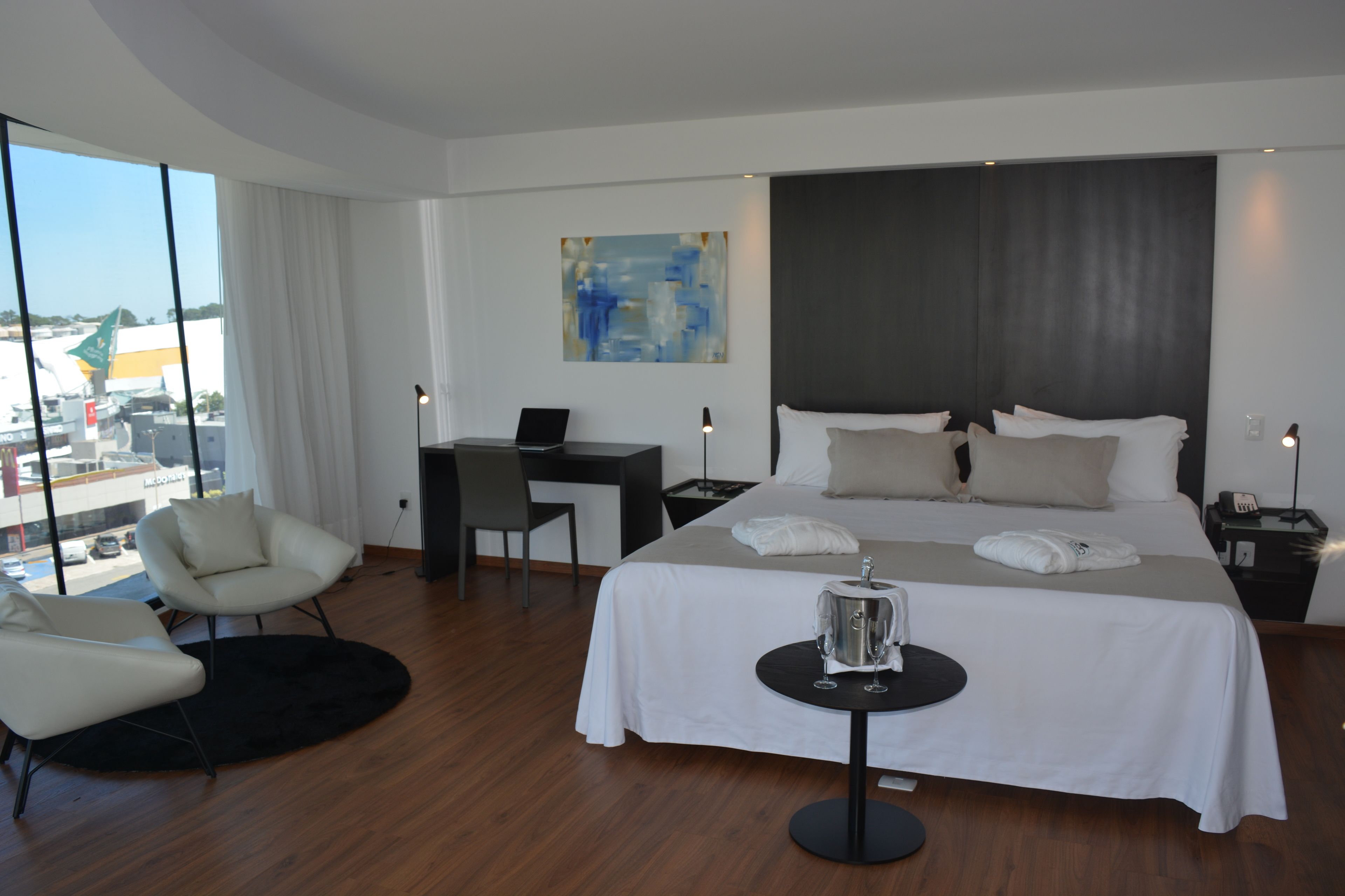 Habitación de hotel moderna con una cama grande, un escritorio, una silla y vistas a la ciudad.