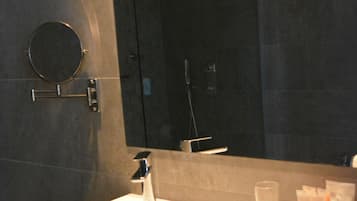 Un baño moderno con un lavamanos blanco, un espejo redondo y un vaso de agua.