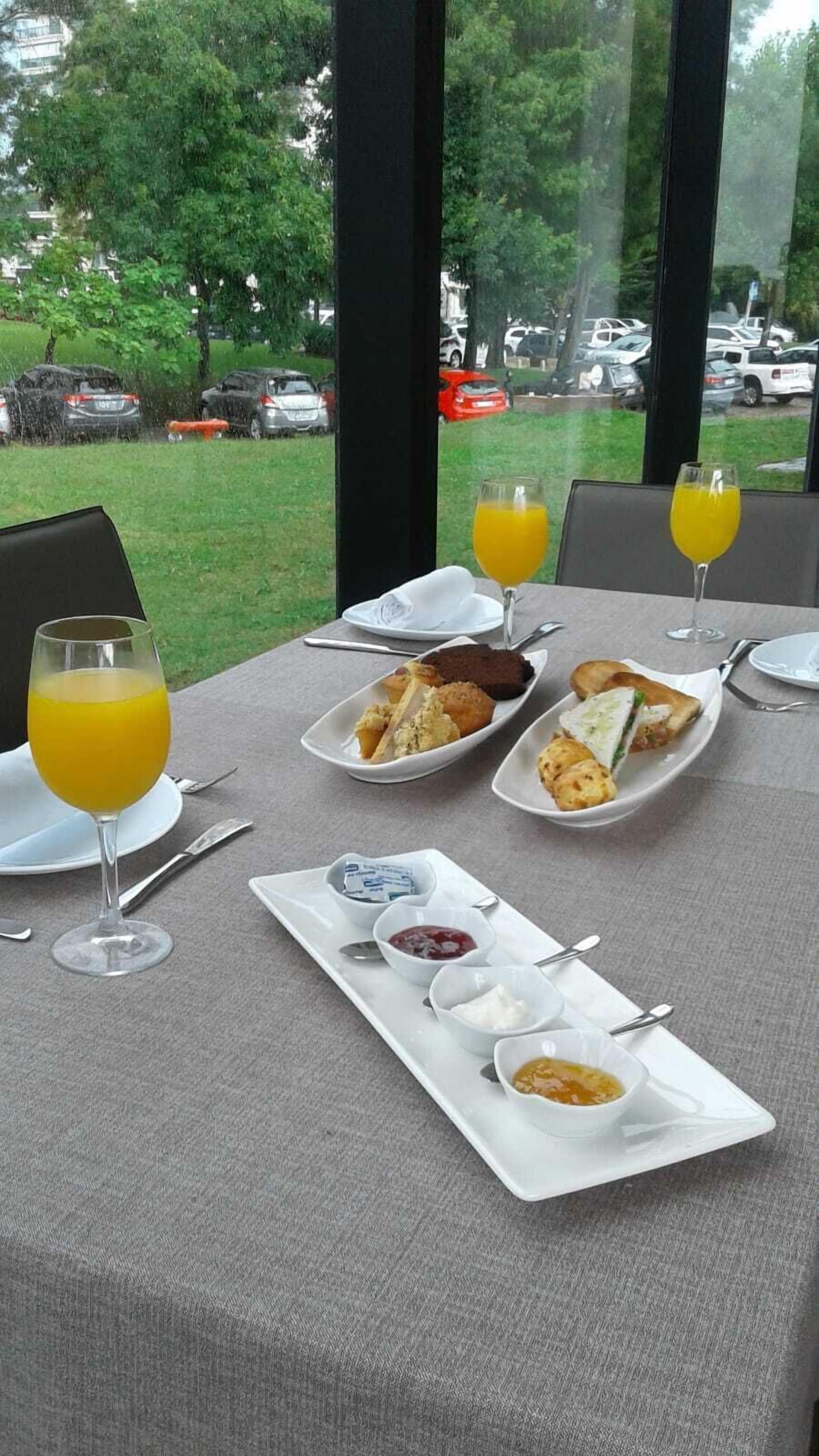 A breakfast table with plates of food, glasses of orange juice, and small bowls of condiments.