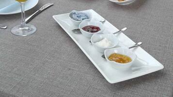 A breakfast table with plates of food, glasses of orange juice, and small bowls of condiments.